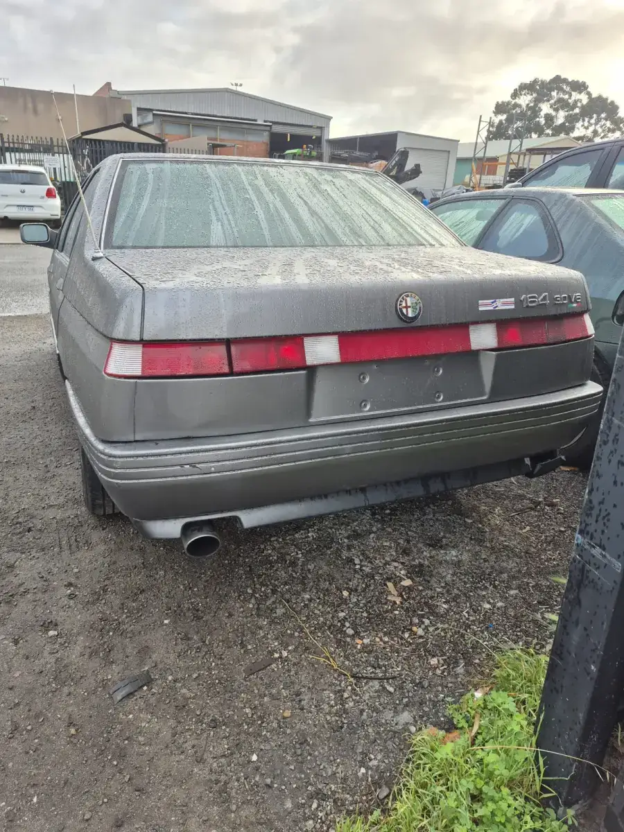 Rear of 1989 Alfa Romeo 164 3.0 V6 showing badges and full-width tail-light bar