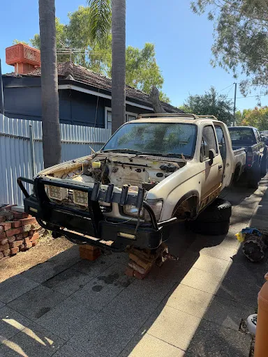 The stripped donor Toyota Hilux sitting on bricks in Trent's driveway, parts removed for another car build.