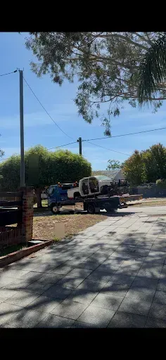 Tow truck winching the wheelless donor Hilux carefully onto the bed without damaging the driveway.